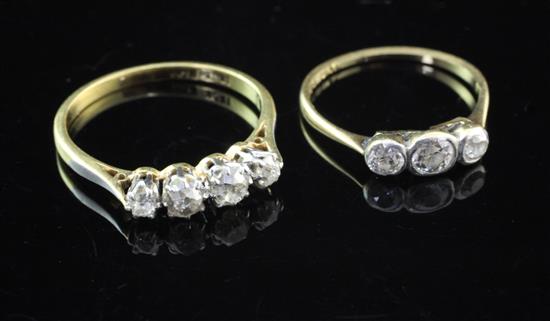 An Edwardian 18ct gold and platinum four stone graduated diamond ring and a similar three stone diamond ring, sizes N & J.